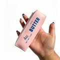 Hand holding a pink container labeled 'Salted Butter' with blue text on a white background squishooshop 