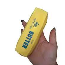 Hand squeezing the yellow butter stick squishy stress ball